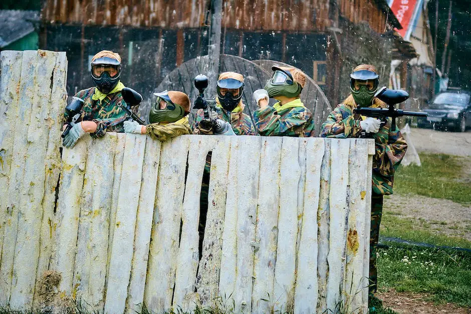 A group of paintball players hiding behind various obstacles on a large outdoor field.