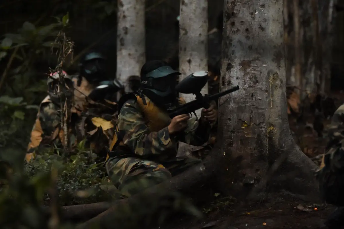 A group of people playing low impact paintball with colorful paintball markers and protective gear.