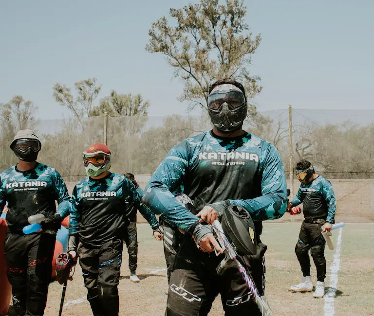 A picture of a paintball field, with players in camouflage gear taking cover behind obstacles and shooting at each other.