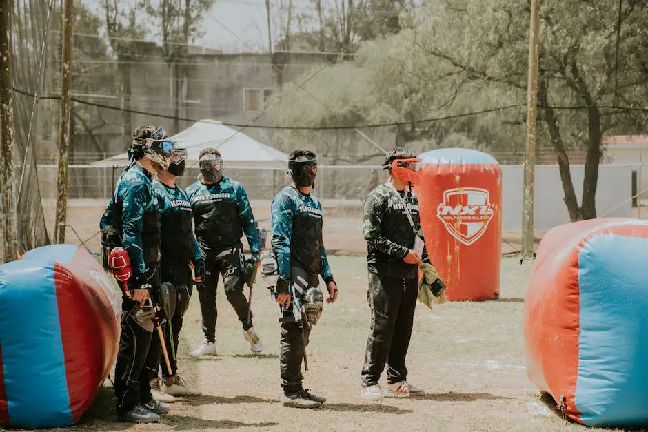 A group of paintball players wearing protective gear and aiming their paintball guns on a designated paintball field.