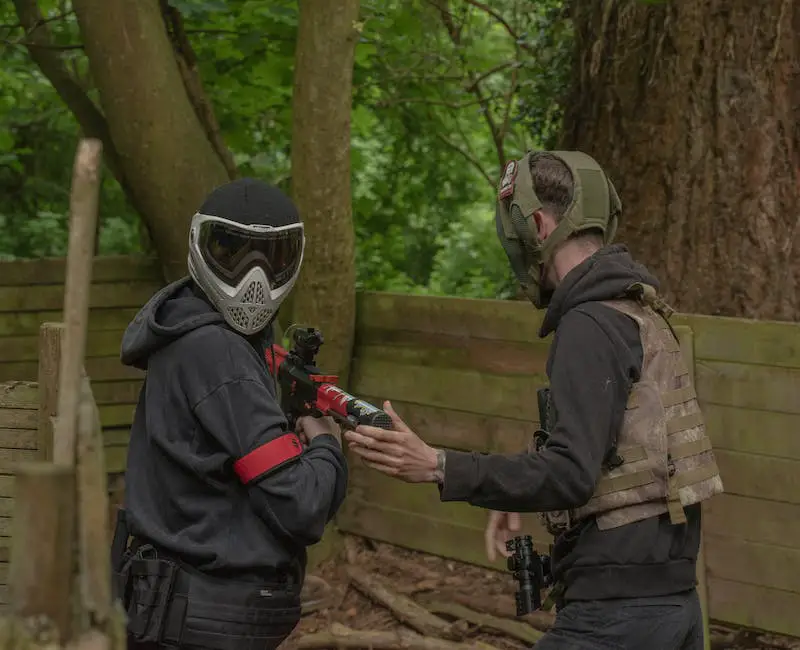 Illustration of a person wearing full-face mask, body armor, and gloves while holding a paintball gun, highlighting the importance of safety measures during paintball games