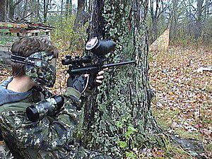 A woodsball paintball player in full gear, carrying a mechanical marker well-suited to the rugged outdoor play environment, representing the alignment of equipment choice and playing style.